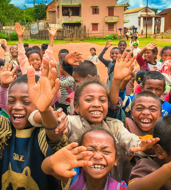 Children smiling and waving up close to the camera.