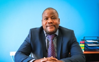 mid shot of a man wearing a suit against a blue blackground