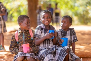 Image of three children with mugs of porridge. 