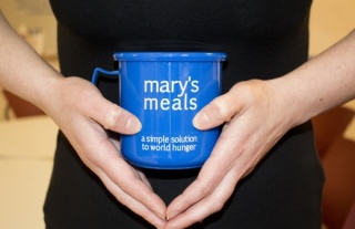 Image of someone holding a Mary's meals mug. 